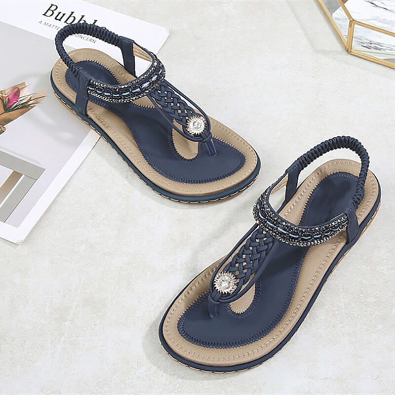 Women's flat gladiator sandals in navy with crystal detail and elastic closure on light background, stylish and comfortable footwear for summer